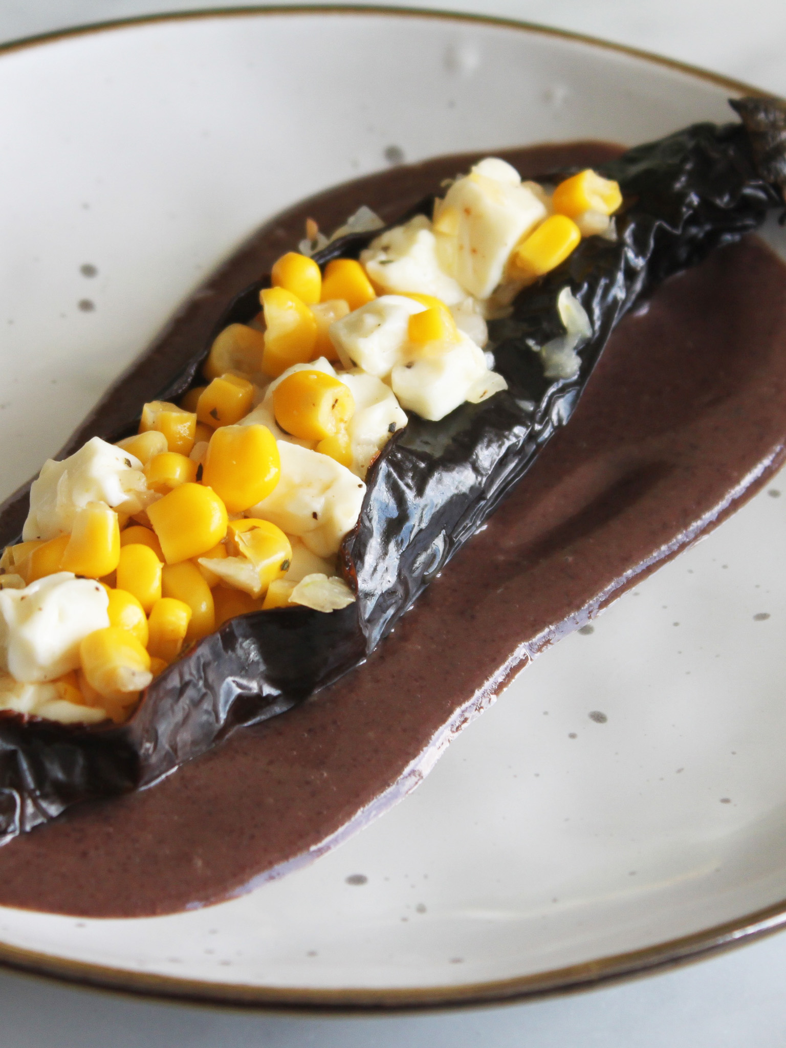 Chiles rellenos de Elote con Queso Panela en cama de Frijol